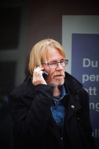 Bearded mature man using smart phone in city