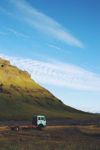 Truck on field by mountain against sky