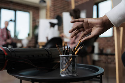 Cropped hand of man picking up pencil