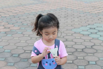 Girl holding shuttlecock on walkway