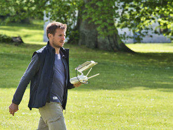 Young man standing on grass against trees