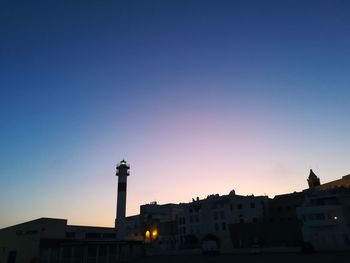 Silhouette buildings against clear sky at sunset