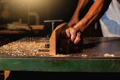 Close-up of a carpenter using a circular saw or a tool to cut wooden planks to make furniture  