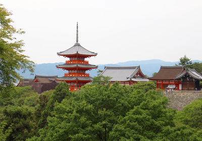 Traditional building by trees against clear sky