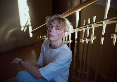 Portrait of sad young man sitting on steps at home