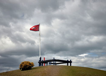 Red flag on bench against sky