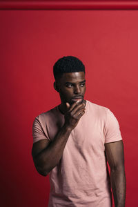 Portrait of man standing against red background