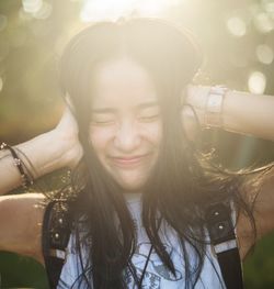 Frustrated young woman with eyes closed covering ears in park at sunset