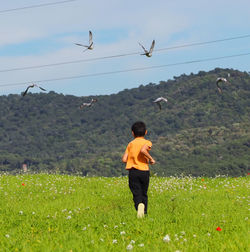 Full length of boy flying on field against sky