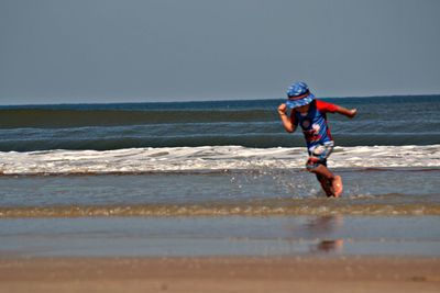 Full length of man surfing on sea against clear sky