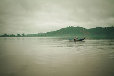 Man on boat in lake against sky