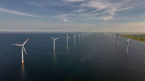 Wind turbines in sea against sky