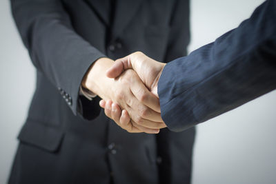 Midsection of businesswoman giving handshake to businessman in office