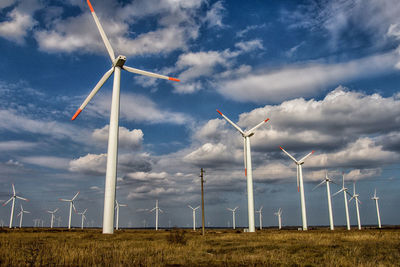 Windmills on field against sky