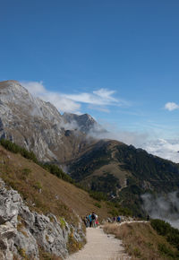 People walking on mountain against blue sky