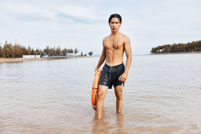 Portrait of shirtless man standing in lake