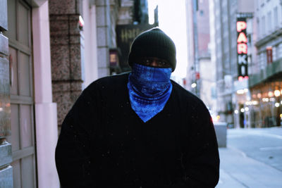 Portrait of man standing in city during winter