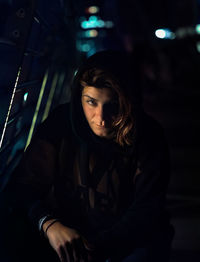 Portrait of beautiful young woman sitting at night