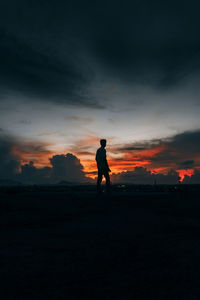 Silhouette man standing on field against sky during sunset
