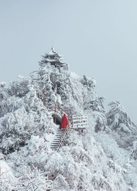 Rear view of man on snowcapped mountain against clear sky