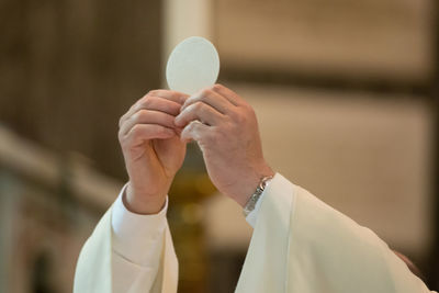 Close-up of hand holding cross against blurred background