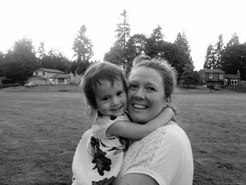 Portrait of happy mother carrying daughter on field