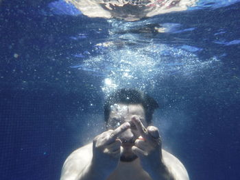 Man showing middle finger while swimming in pool