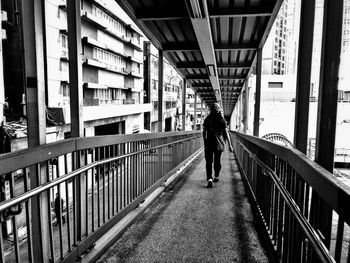 Rear view of woman walking on bridge in city