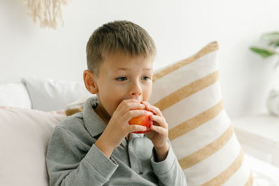 Boy blowing bubbles on bed at home