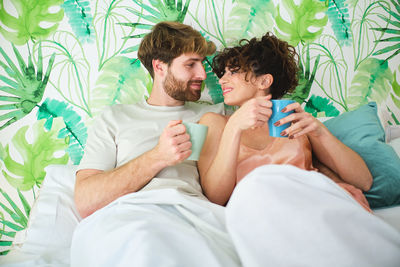 Young couple sitting on bed at home