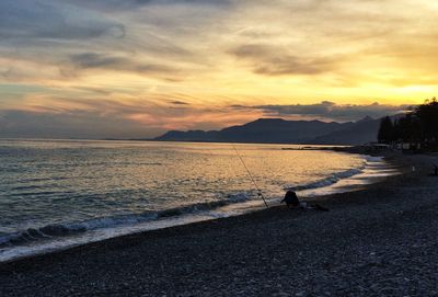 Scenic view of sea against cloudy sky during sunset