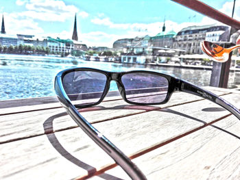 Close-up of sunglasses on table in city against sky