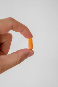 Close-up of hand holding orange over white background