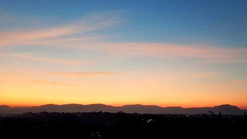 Scenic view of silhouette mountains against romantic sky at sunset