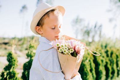 Handsome boy holding a beautiful bouquet of flowers in summer