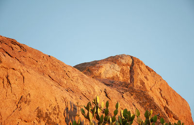 Low angle view of rocky mountains against clear blue sky