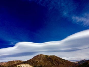 High section of snowcapped mountain against blue sky