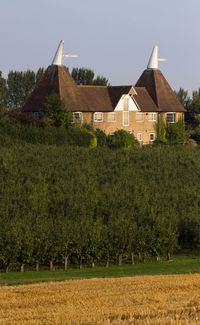 House on field by houses against sky