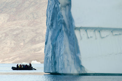 People on boat sailing in sea against sky