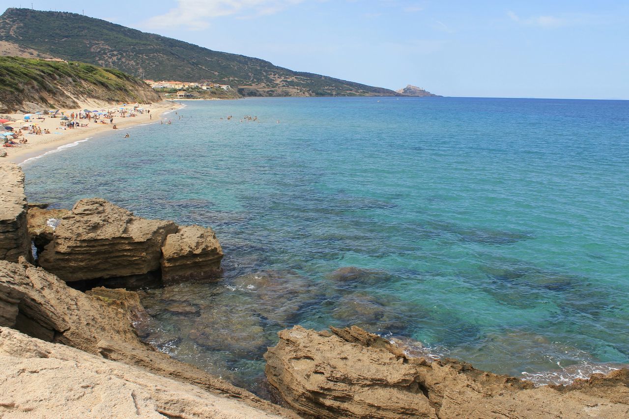 sea, mountain, tranquil scene, water, beach, scenics, shore, tranquility, beauty in nature, rock - object, coastline, stone - object, nature, non-urban scene, calm, day, sky, remote, outdoors, blue, vacations, summer, rocky, seascape, mountain range, no people, tourism, ocean