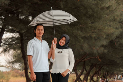 Portrait of a smiling young woman standing in rain