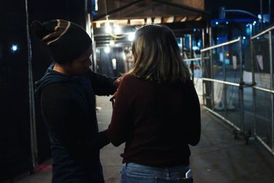 Rear view of friends standing in illuminated city at night