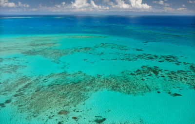 Scenic view of great barrier reef and turquoise sea against blue sky