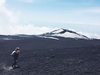 Woman standing on snow covered mountain against sky