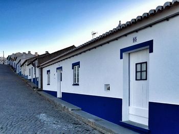 Empty street amidst buildings against blue sky