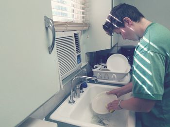 Woman washing dishes at kitchen sink