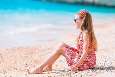 Side view of girl sitting on beach