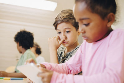 Boys using digital tablet while learning at classroom