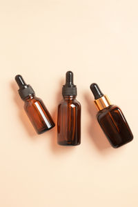 Amber glass dropper bottles different sizes on beige background. cosmetic container mock-ups. 