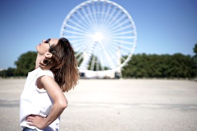 Side view of mature woman wearing sunglasses standing against clear sky during sunny day